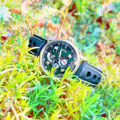 CHRONOSWISS Flying Regulator - Uhr liegend in einer Rasenfläche, von vorne abgelichtet