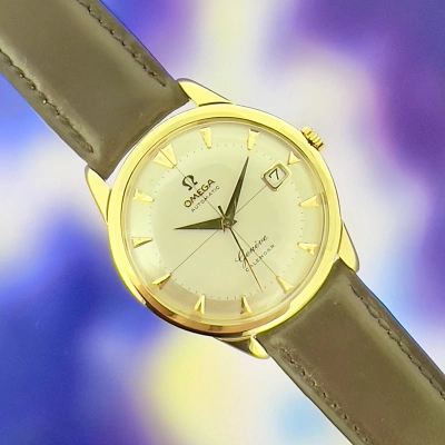 OMEGA Genève - Golduhr liegend auf einem Foto mit verschwommenen, violett-blauen Mustern